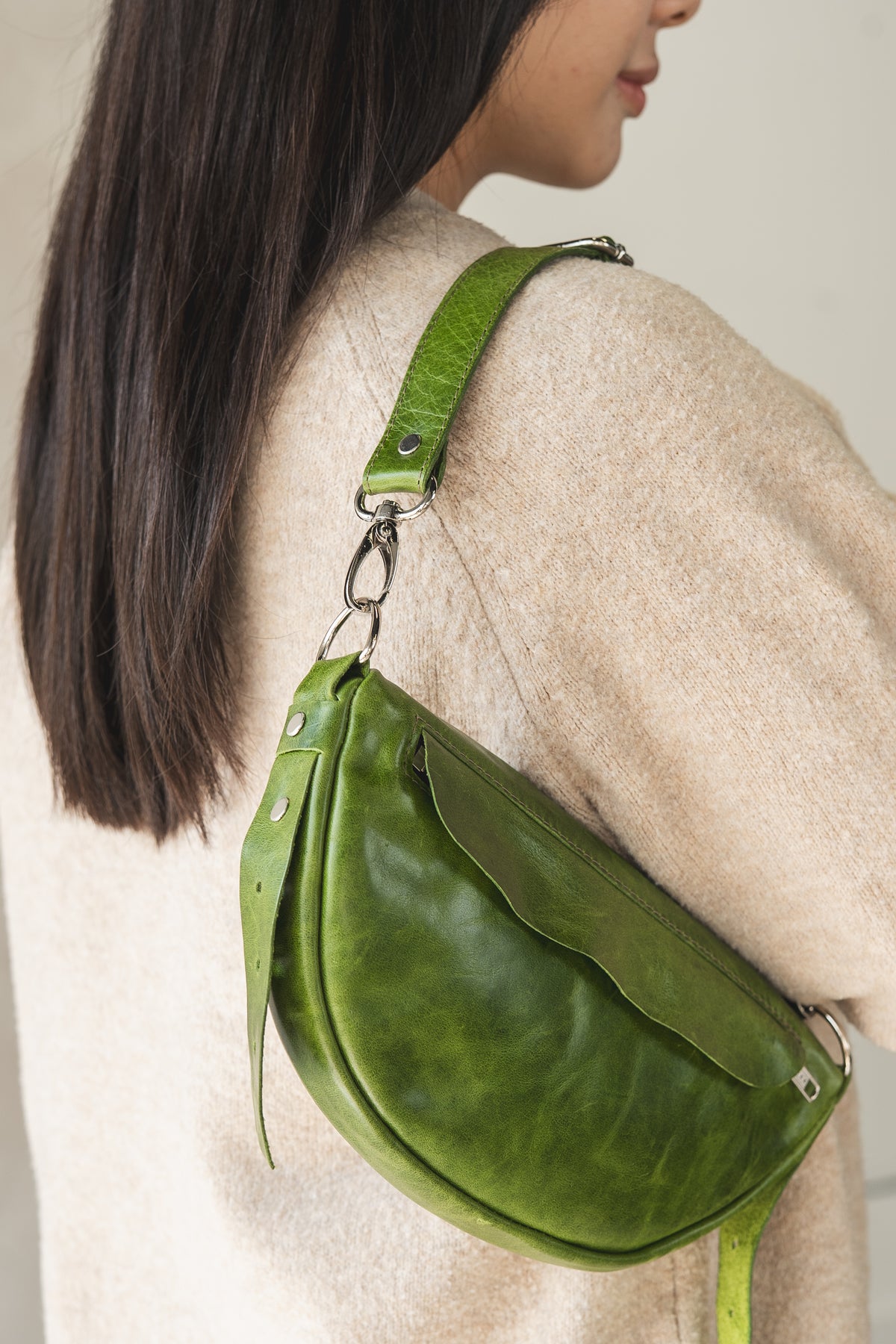 Green leather bag worn by a person with a neutral background