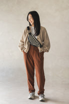 Woman looking down to the side, smiling, wearing a handcrafted leather woven crossbody bag