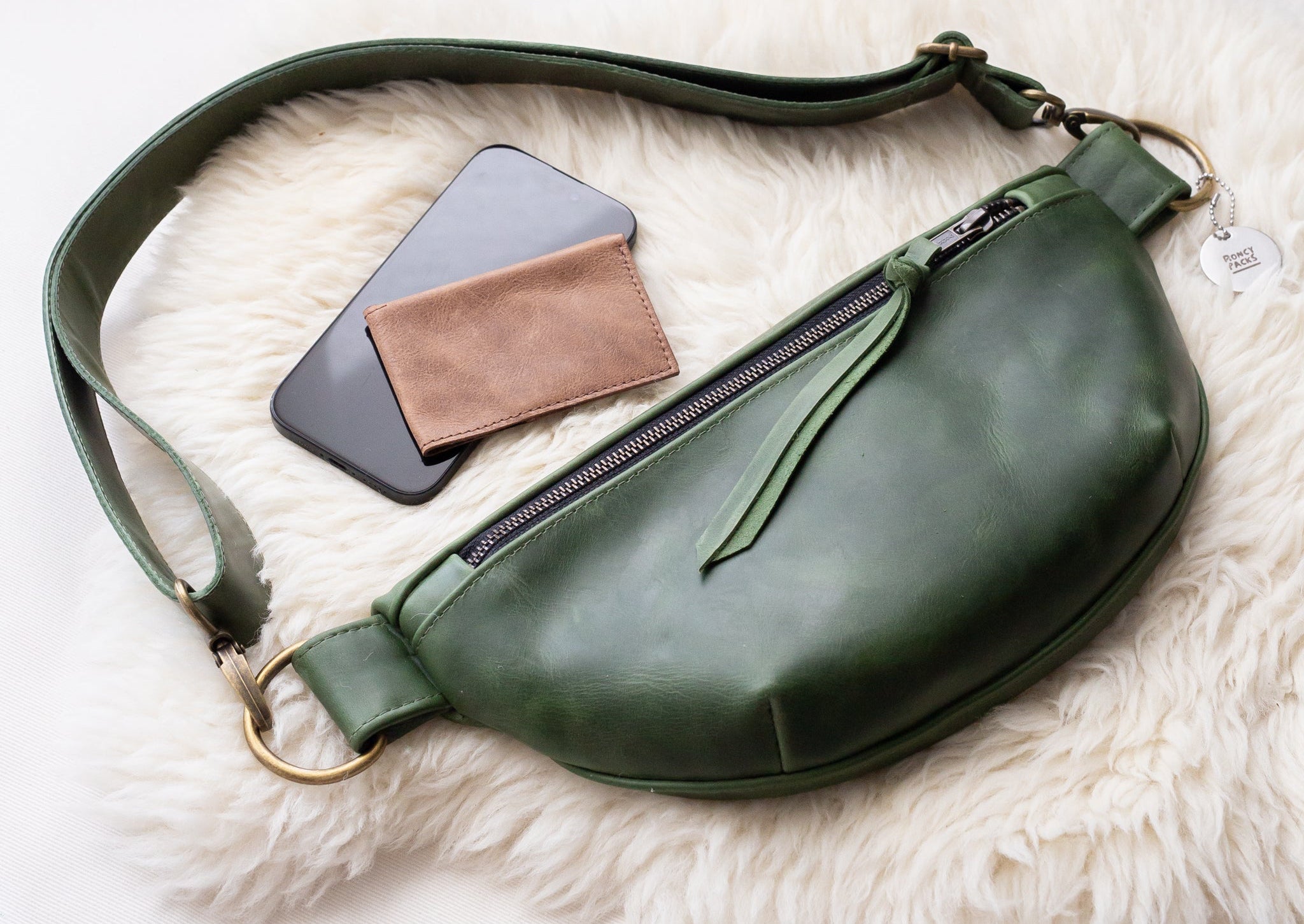 Green leather bag with phone and wallet on a white fur surface