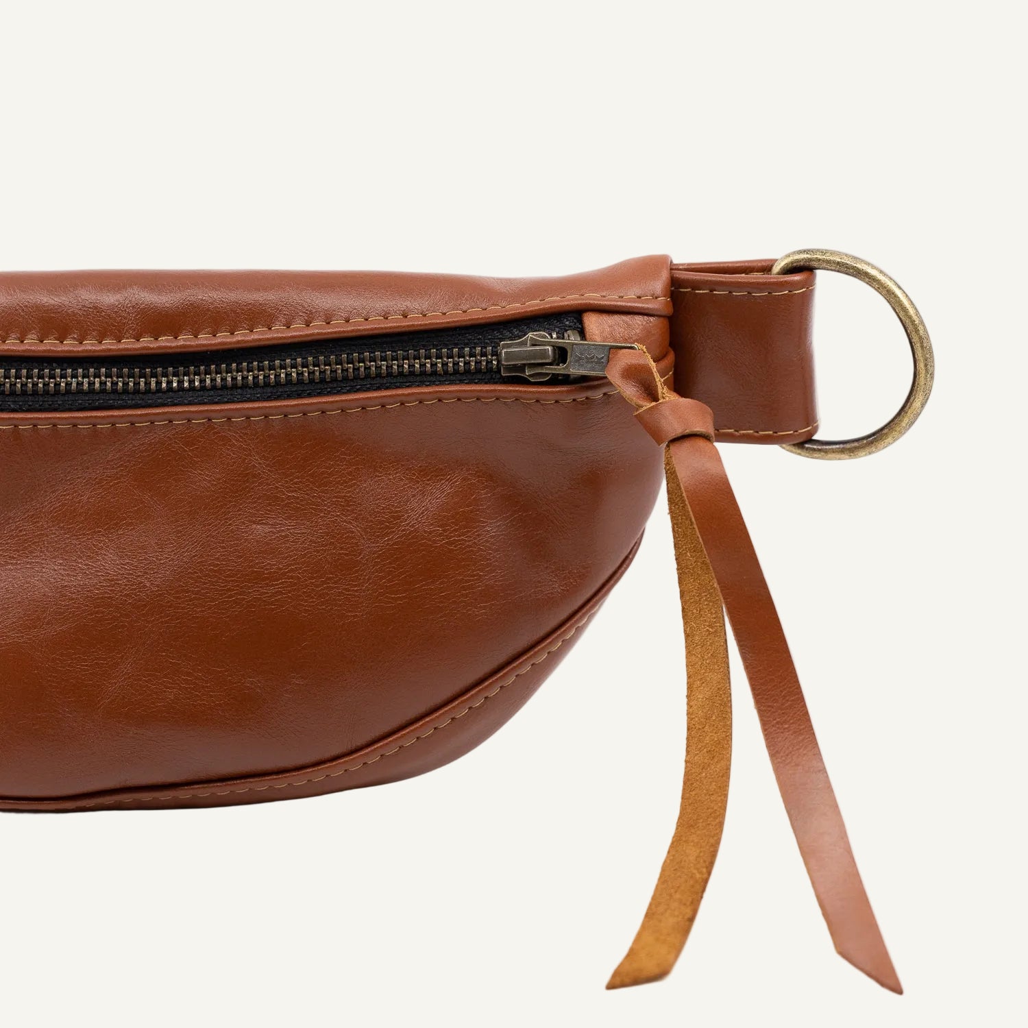 Brown leather waist bag with a strap on a white background