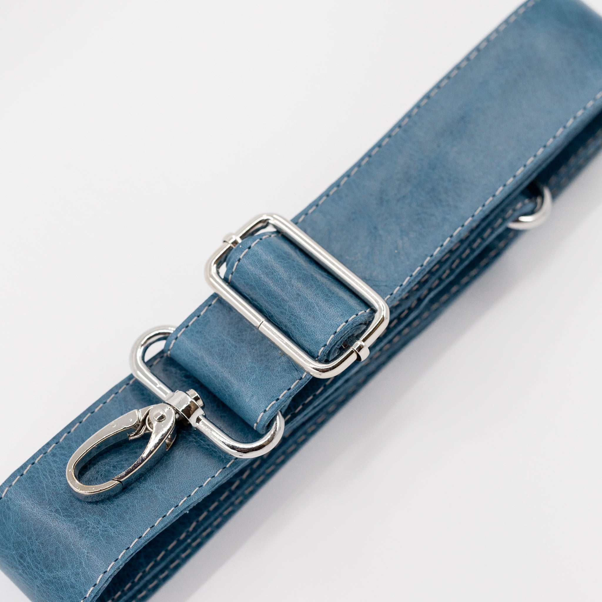 Blue leather strap with silver hardware on a light gray background