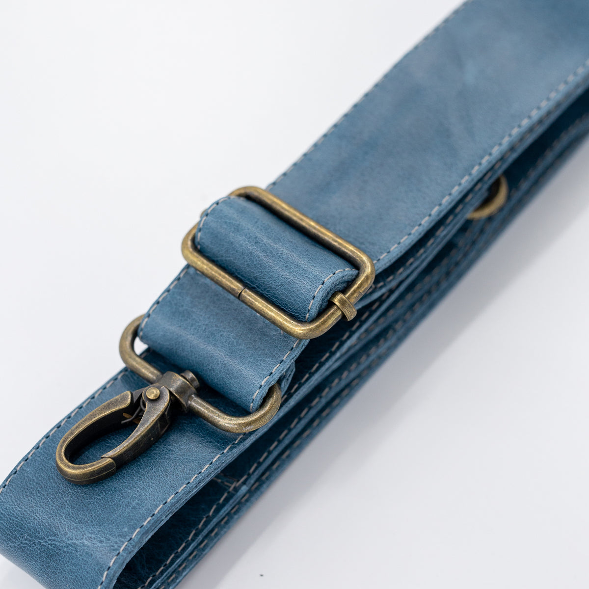 Close-up of a blue strap with brass hardware on a white background