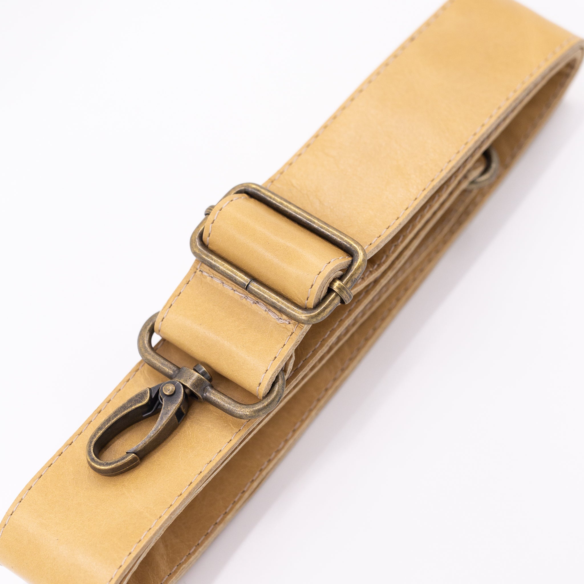 Beige leather strap with brass clips on a white background