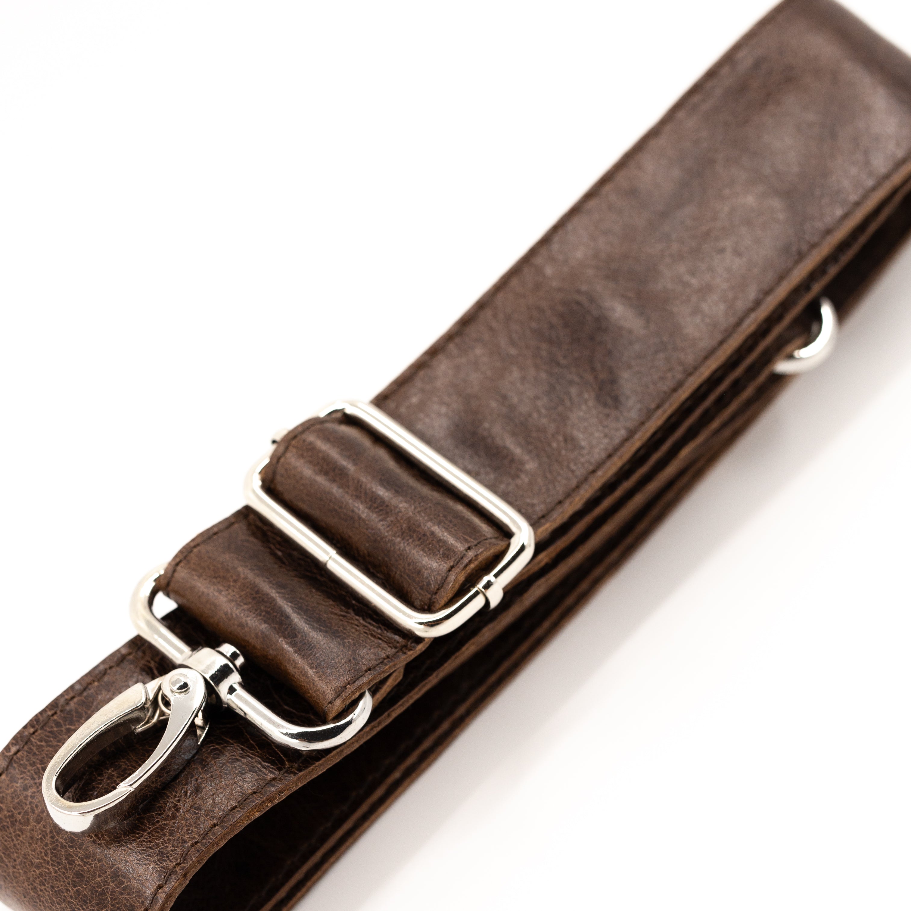 A close-up of a dark brown leather strap with silver-tone metal hardware, including a buckle, adjustment loops, and a swivel clasp, photographed on a clean white background.