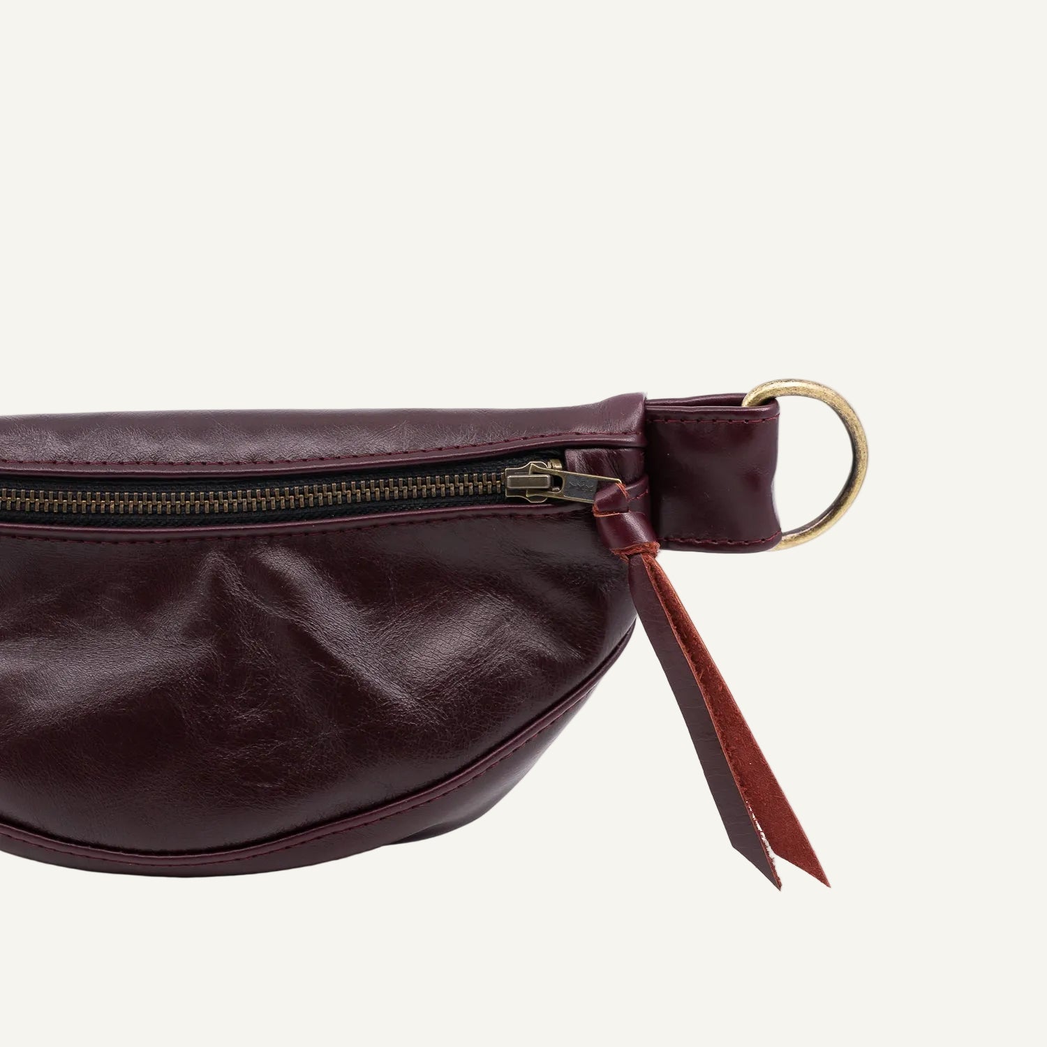Burgundy leather fanny pack with a gold zipper on a white background