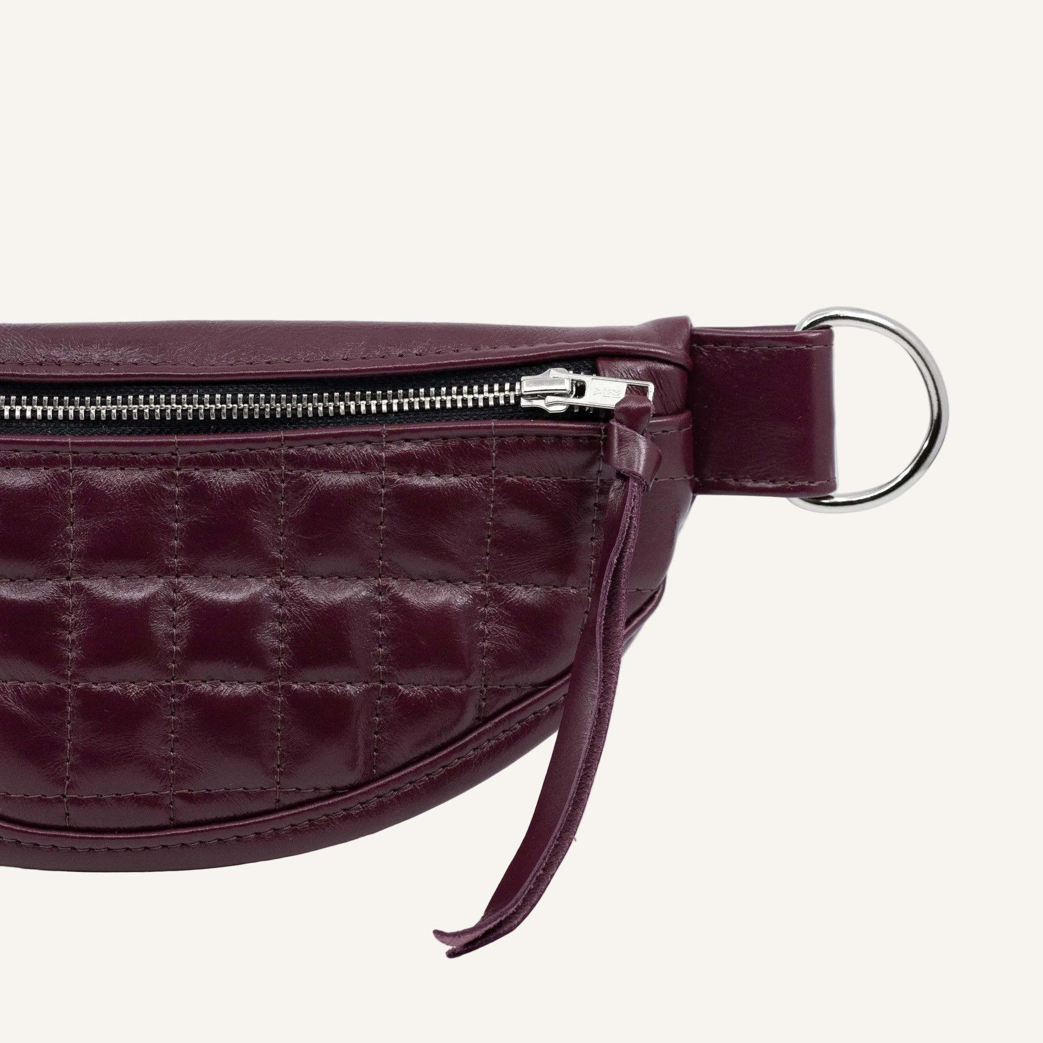 A quilted purple wine leather handbag with a zippered interior, pairs with a detachable strap.