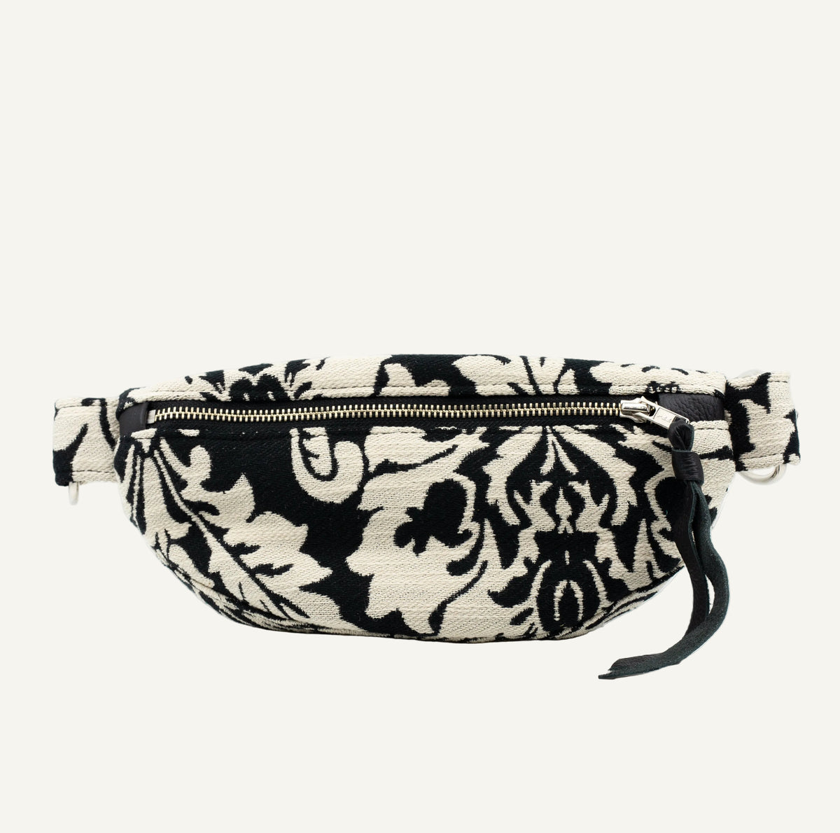 A black and off-white damask patterned waist bag with a chrome zipper and a black leather tassel pull, shown against a plain white background.
