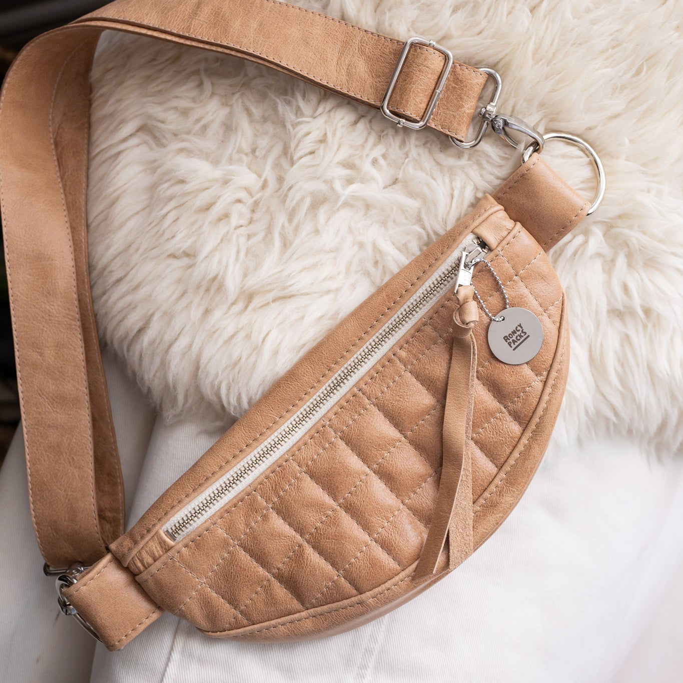 Quilted beige crossbody bag on a fluffy white surface