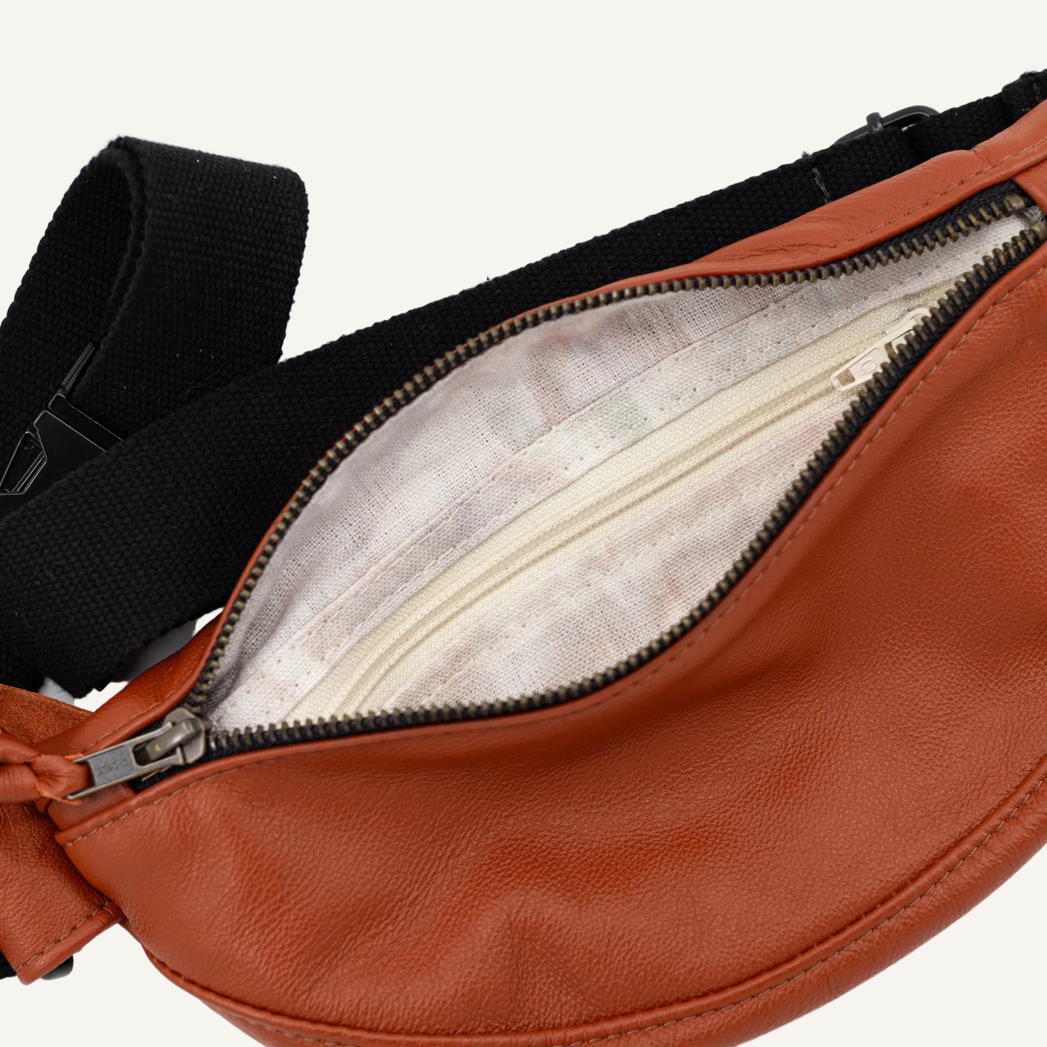 burnt orange leather fanny pack with black strap on a white background