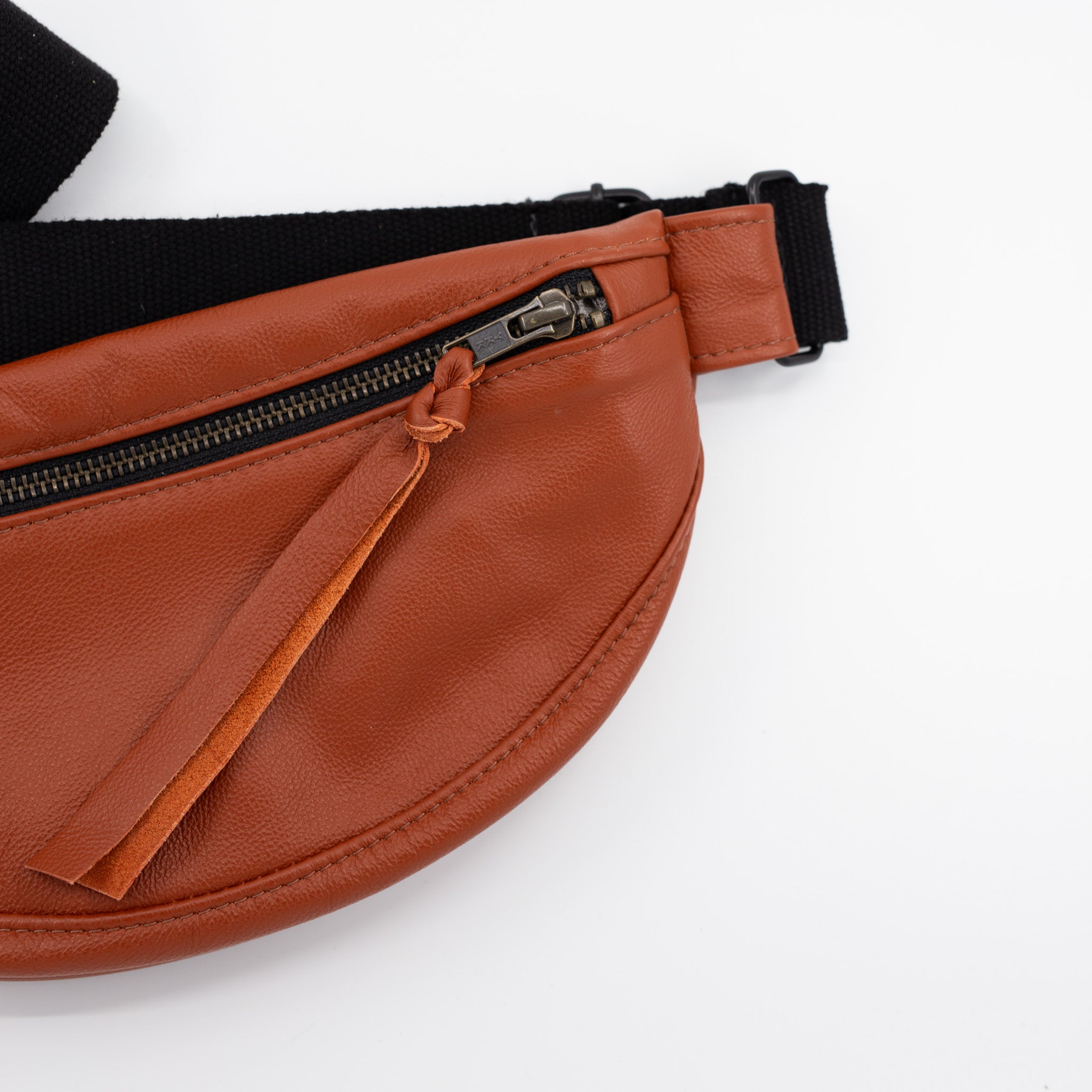 burnt orange leather fanny pack with a black zipper on a white background