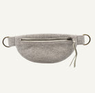A light gray textured fabric waist bag with a front zipper pocket, bronze metal D-rings, and a small leather pull tab, shown against a plain white background.