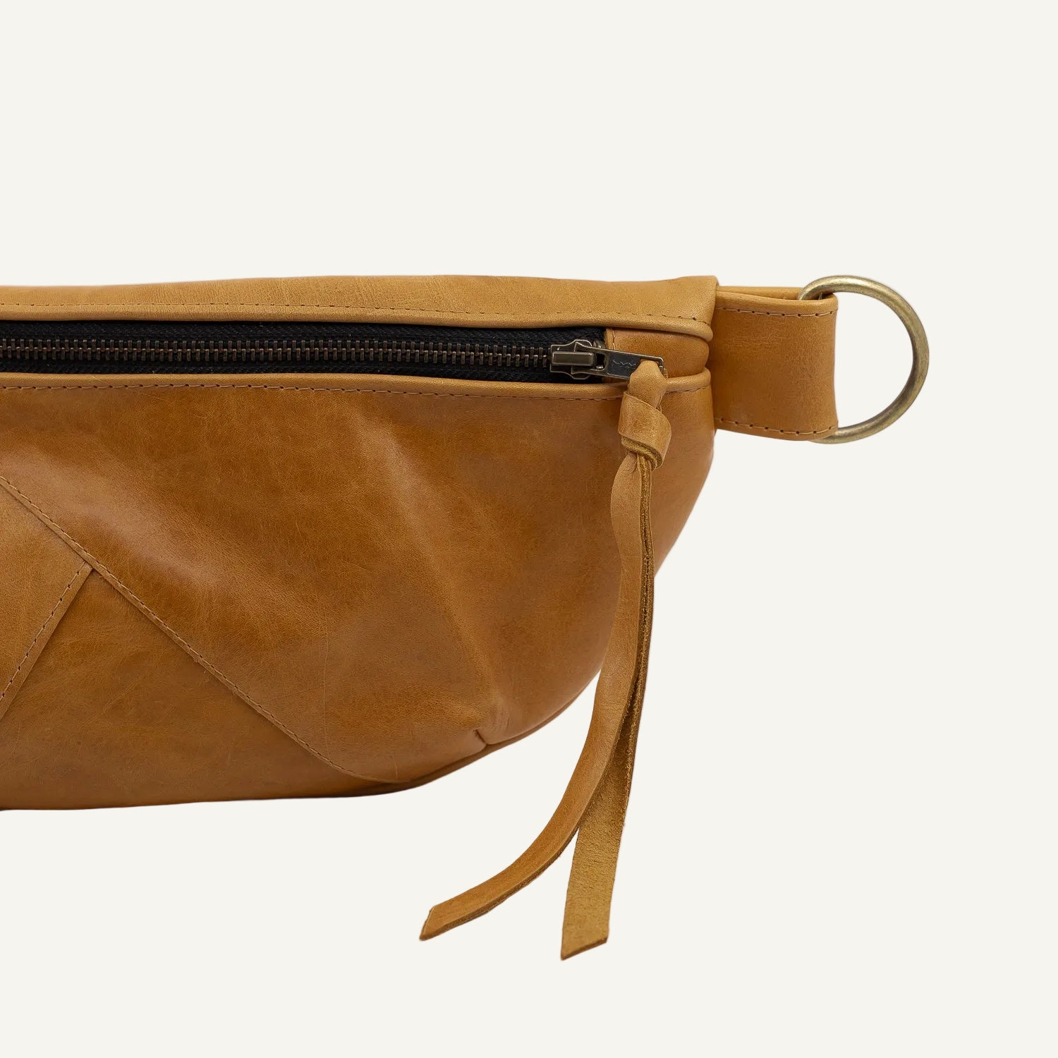 Brown leather waist bag with a black zipper on a white background