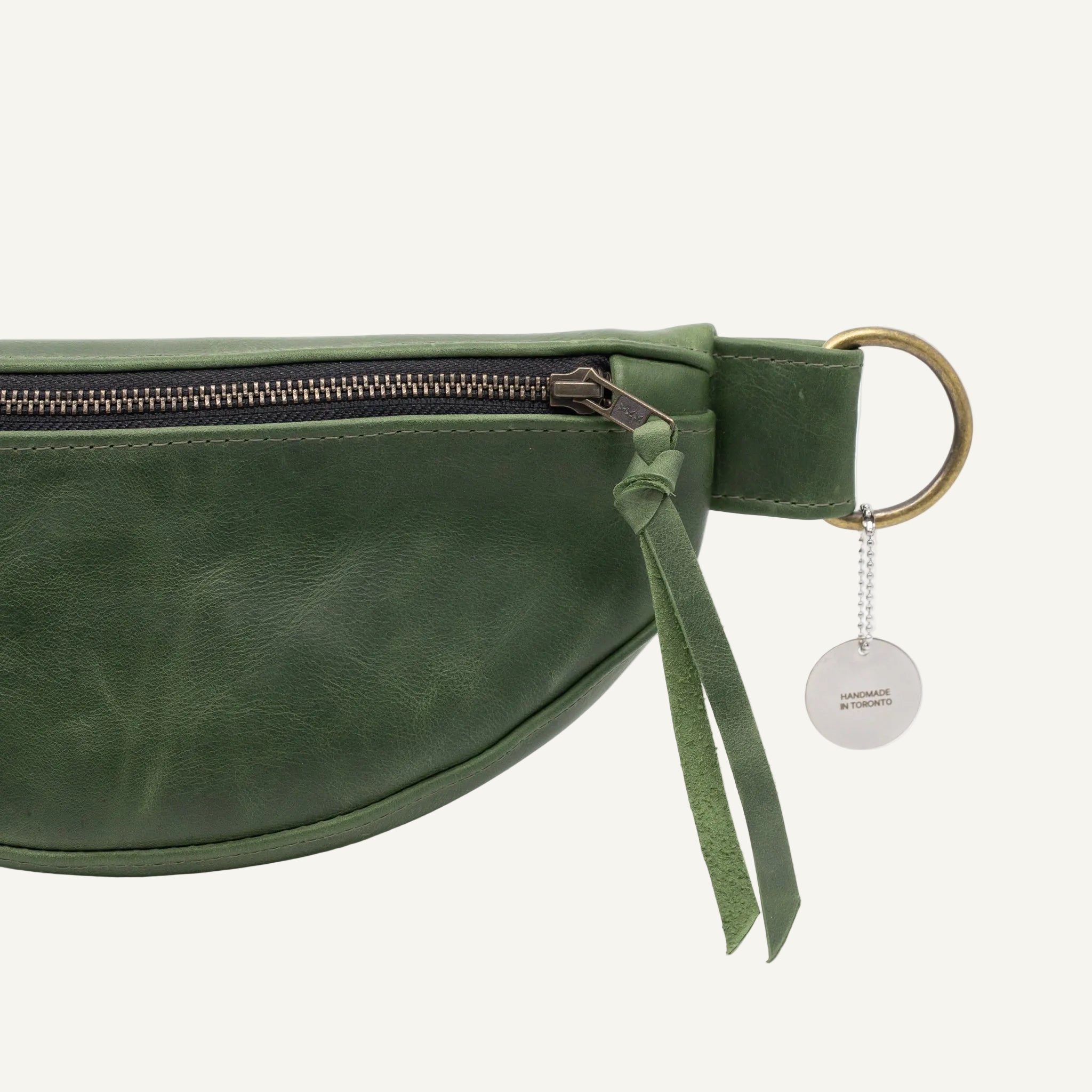 Green leather waist bag and gold zipper on a white background
