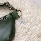 Green leather bag with a tag on a white fluffy surface