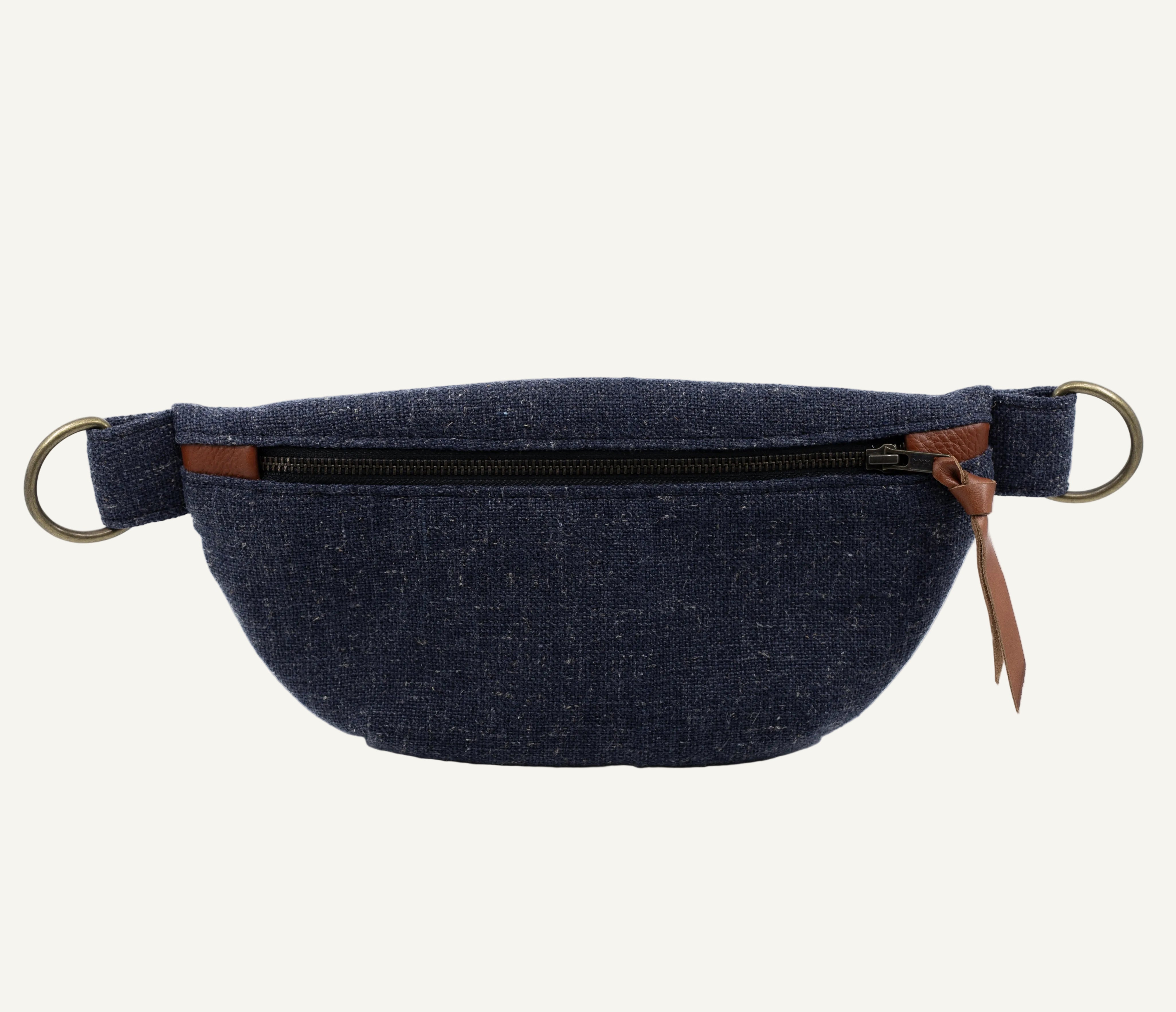 A navy blue canvas fanny pack with a brown leather zipper pull and brass hardware, shown against a plain white background.