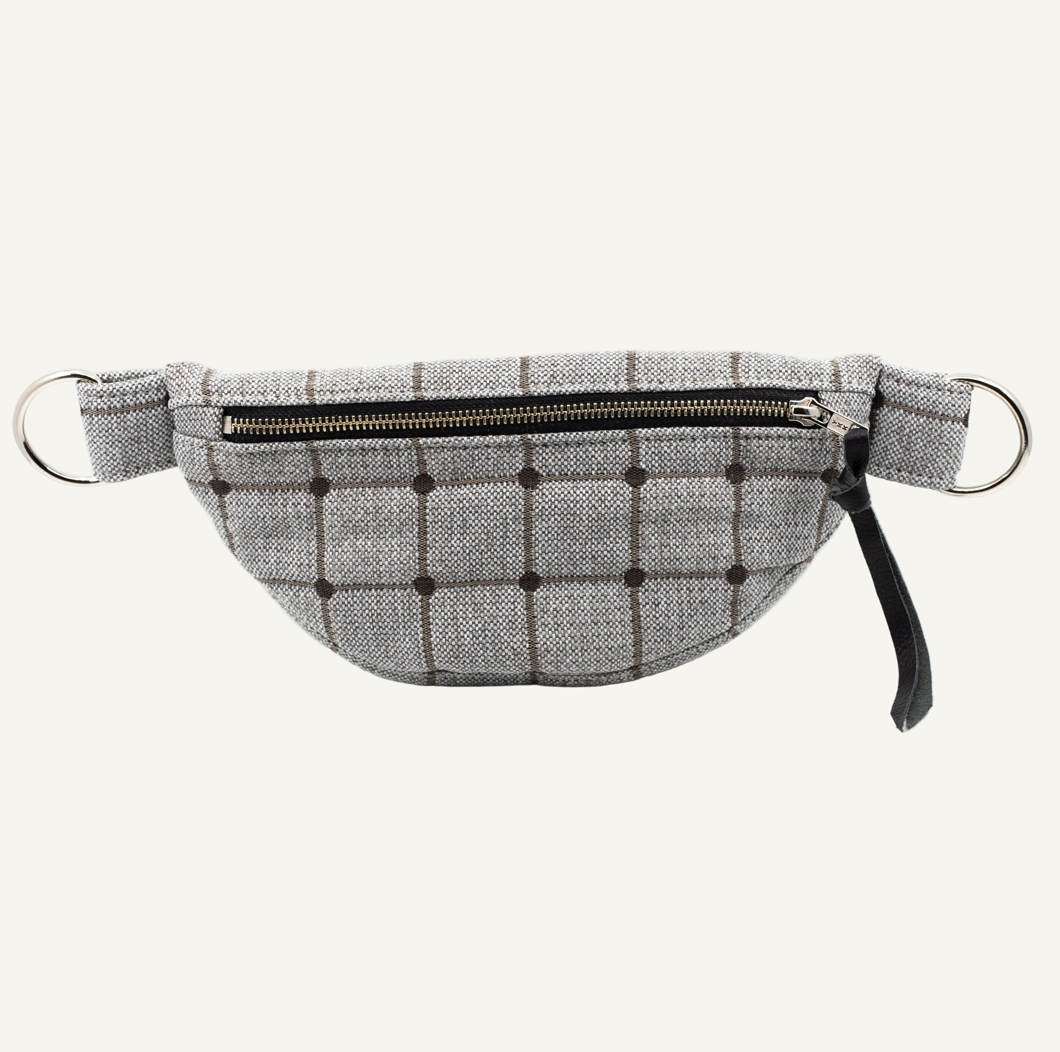 A gray and black plaid fabric fanny pack with a top zipper, and black leather tassel, shown against a plain white background.
