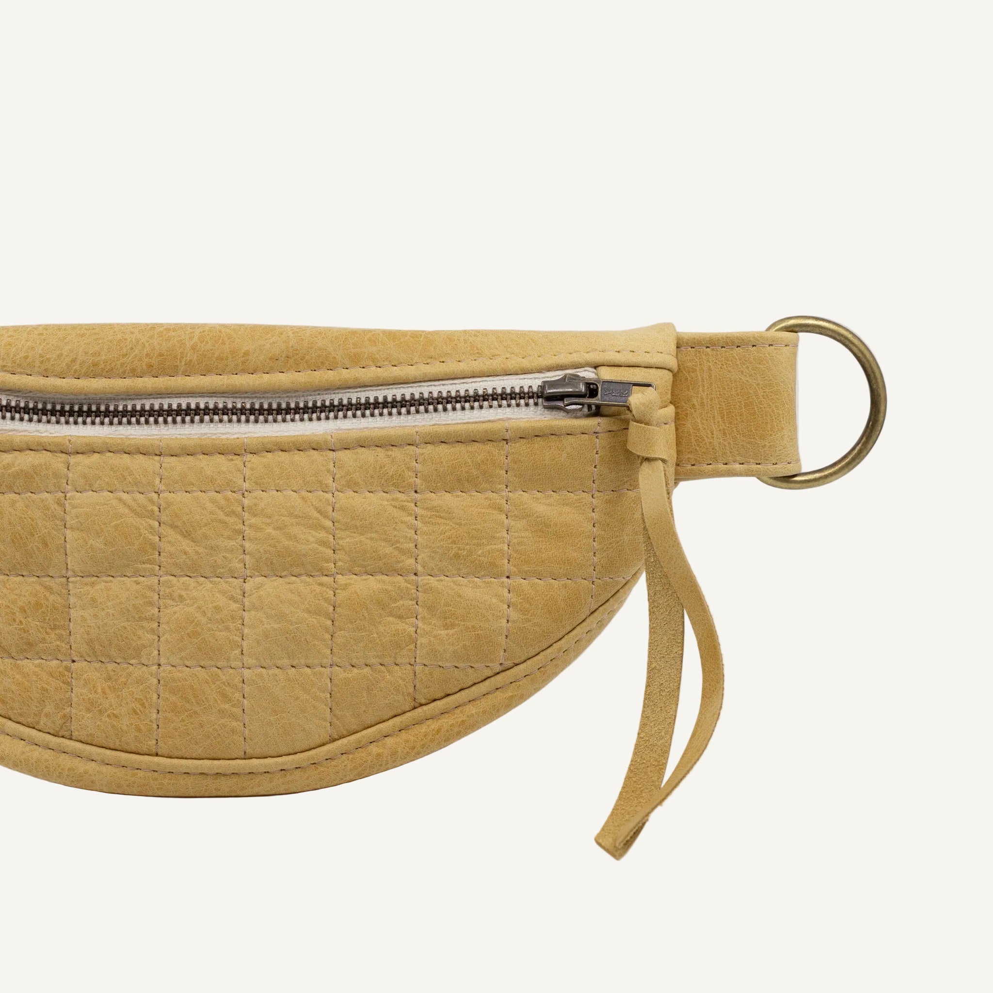 Quilted yellow fanny pack with a gold zipper on a white background