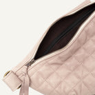 Close-up of a quilted light mauve shoulder bag with a open zipper showing a dark brown interior lining.