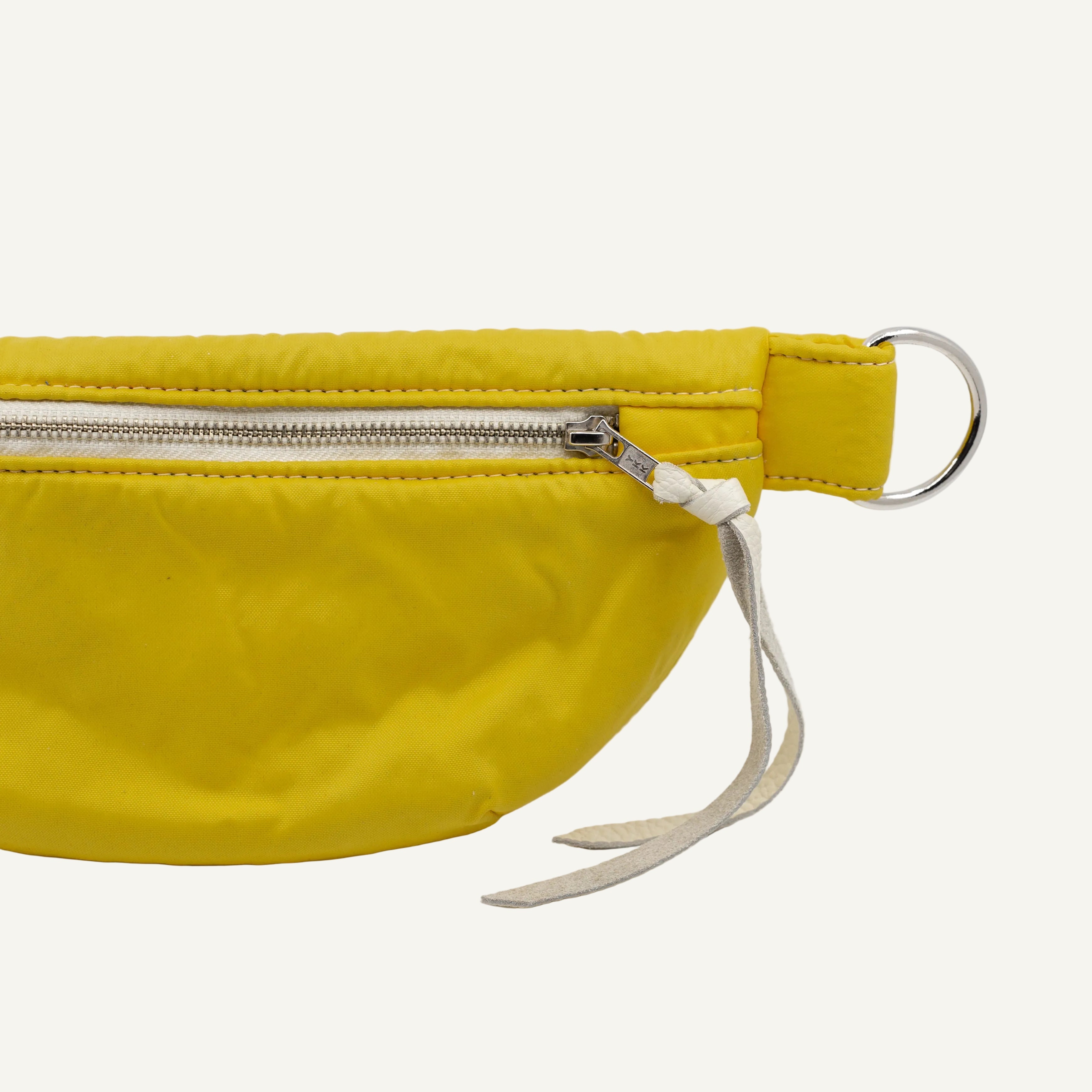 Yellow waist bag with a silver zipper on a white background