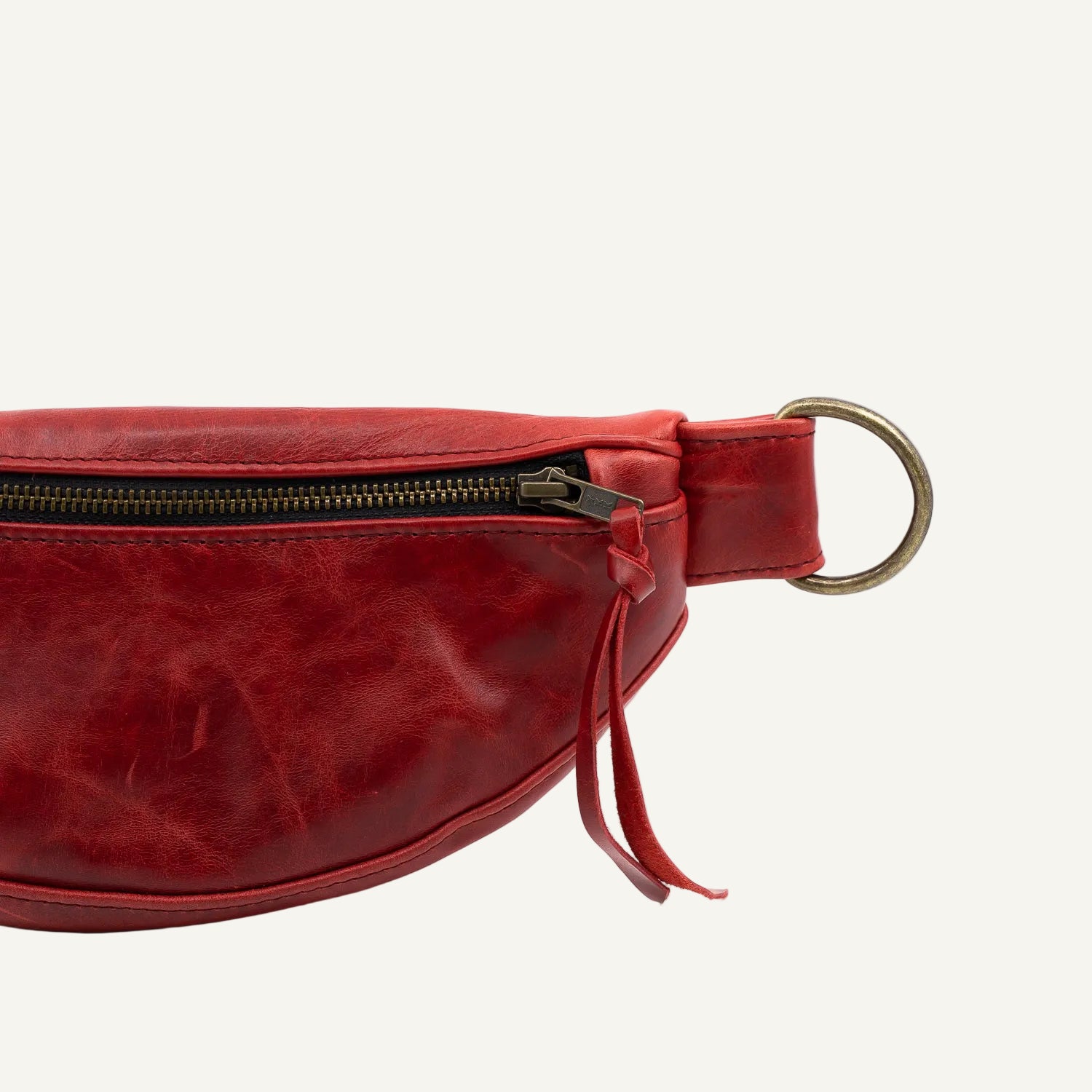 Red leather waist bag with a gold zipper and ring on a white background