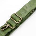 Green leather strap with brass clips on a white background