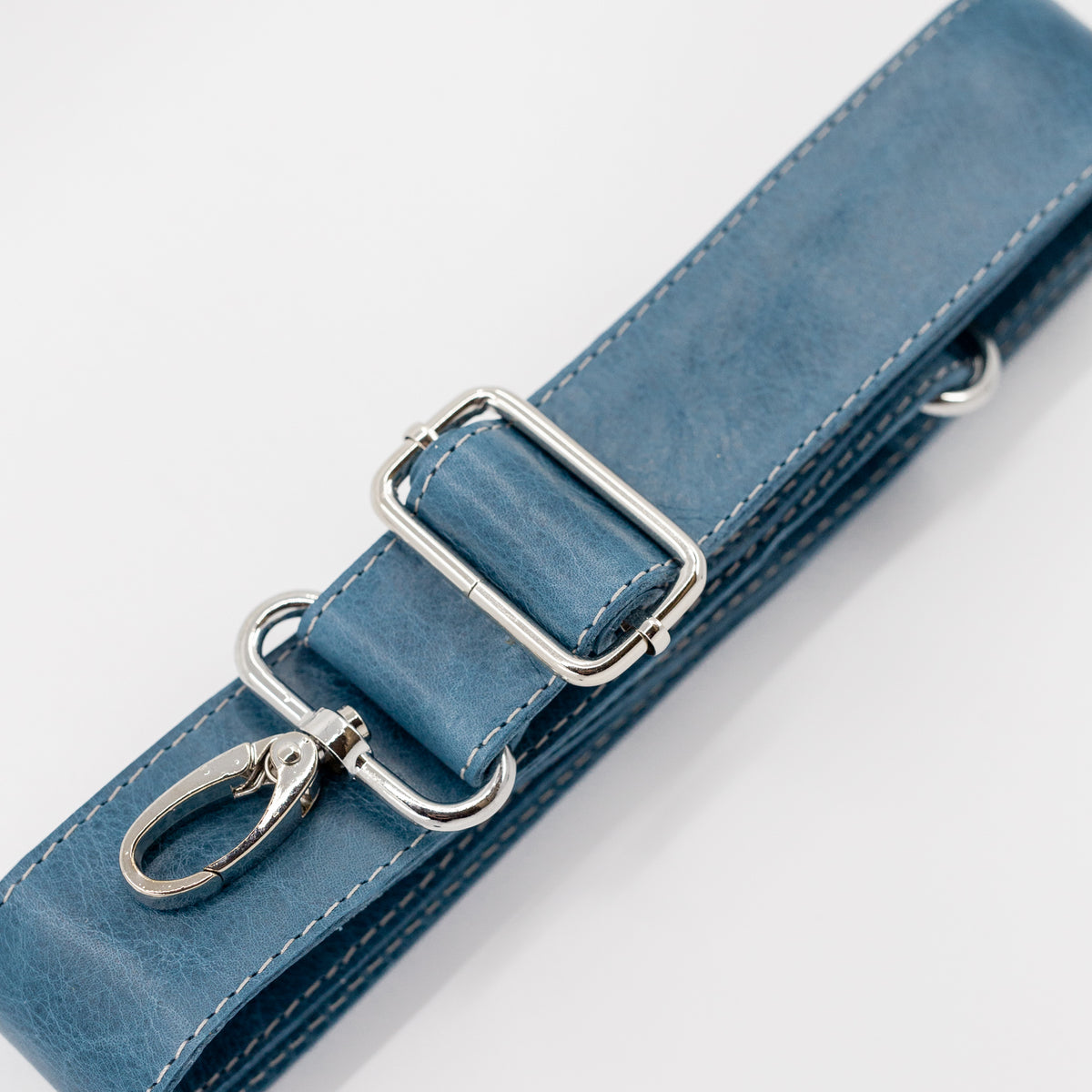 Blue leather strap with silver hardware on a light gray background