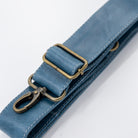 Close-up of a blue strap with brass hardware on a white background