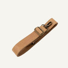 A tan leather camera strap with an adjustable brass buckle and a metal clip, shown on a plain off-white background.