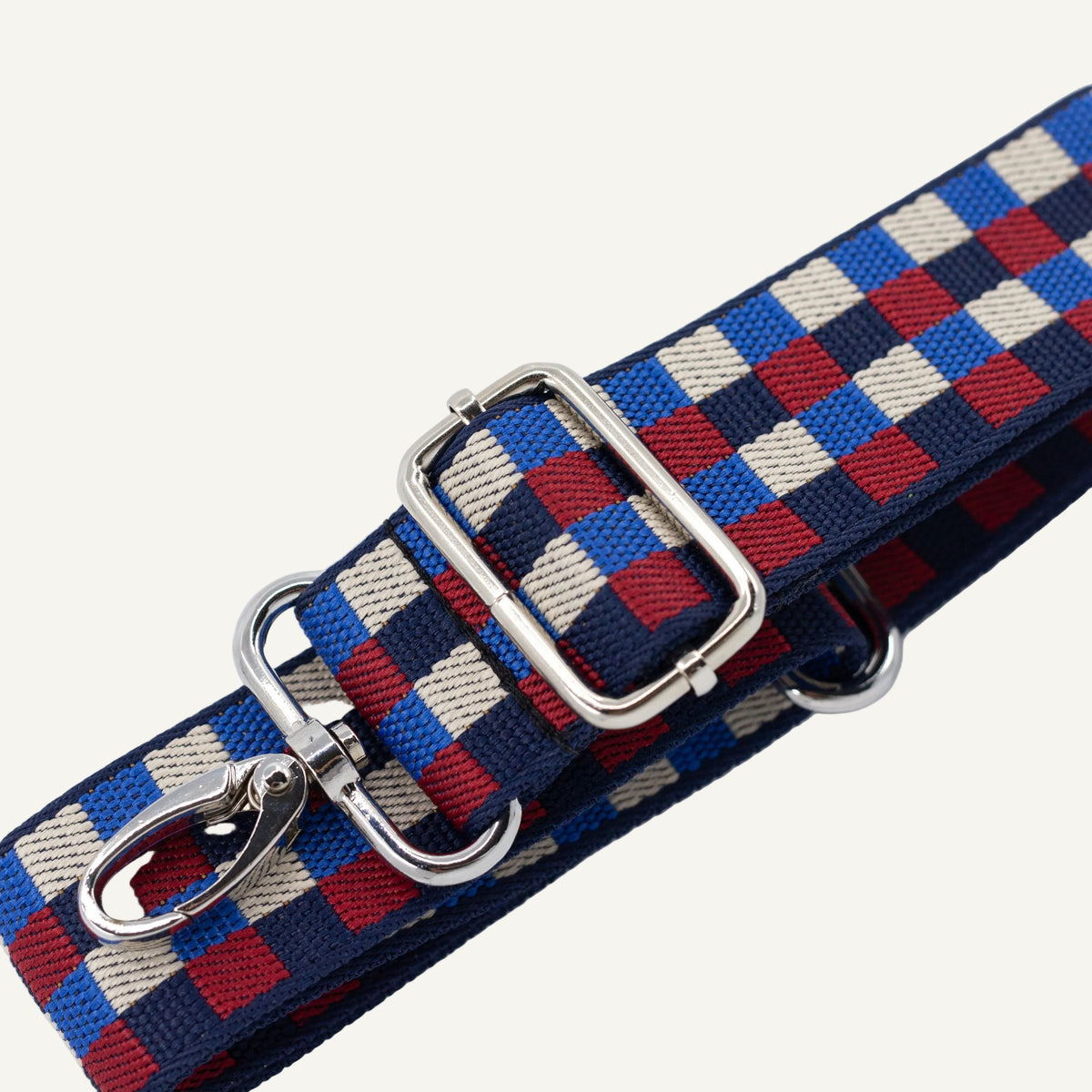 Woven belt with checkered pattern and metal clips on a light gray background