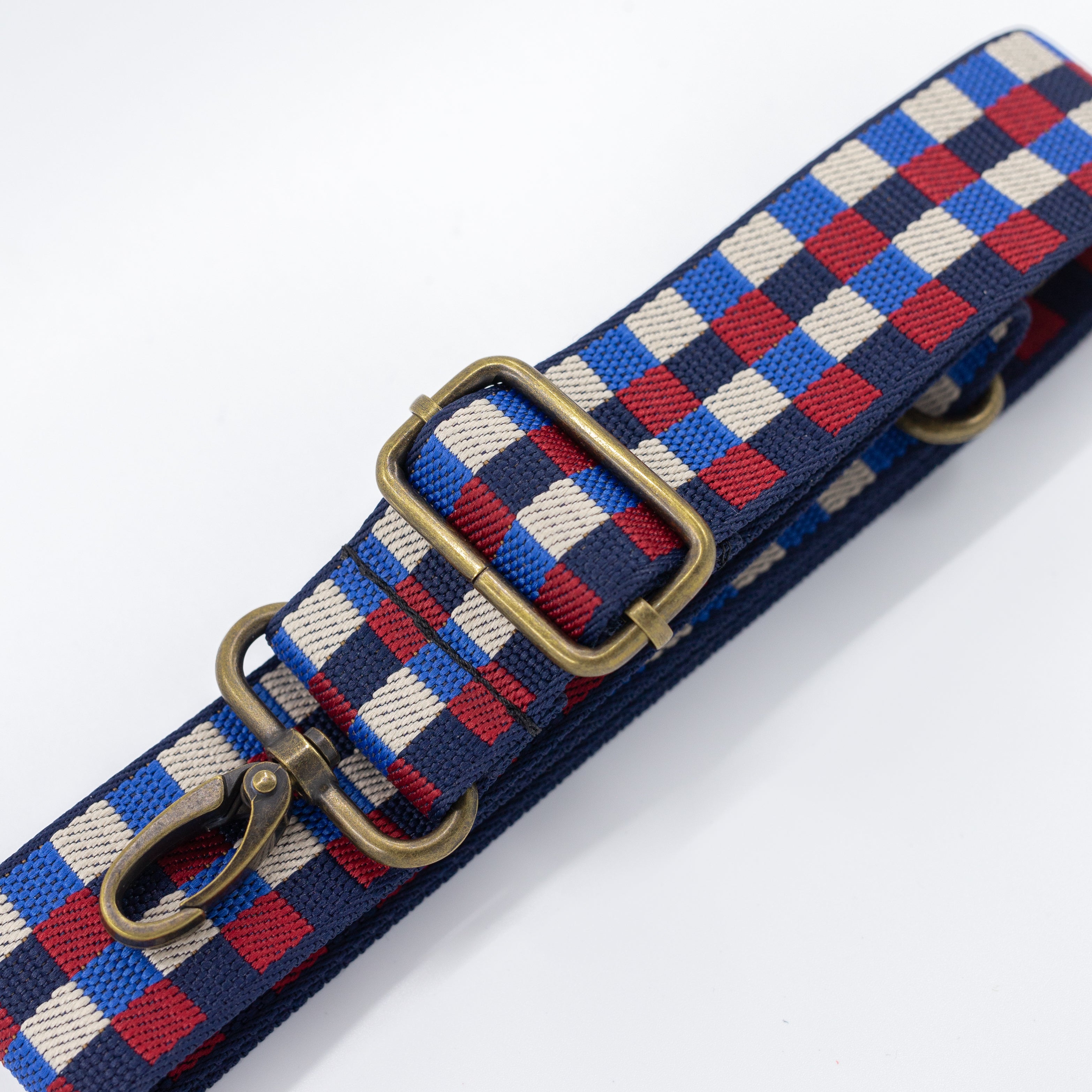 Woven strap with a checkered pattern in red, blue, and beige on a white background