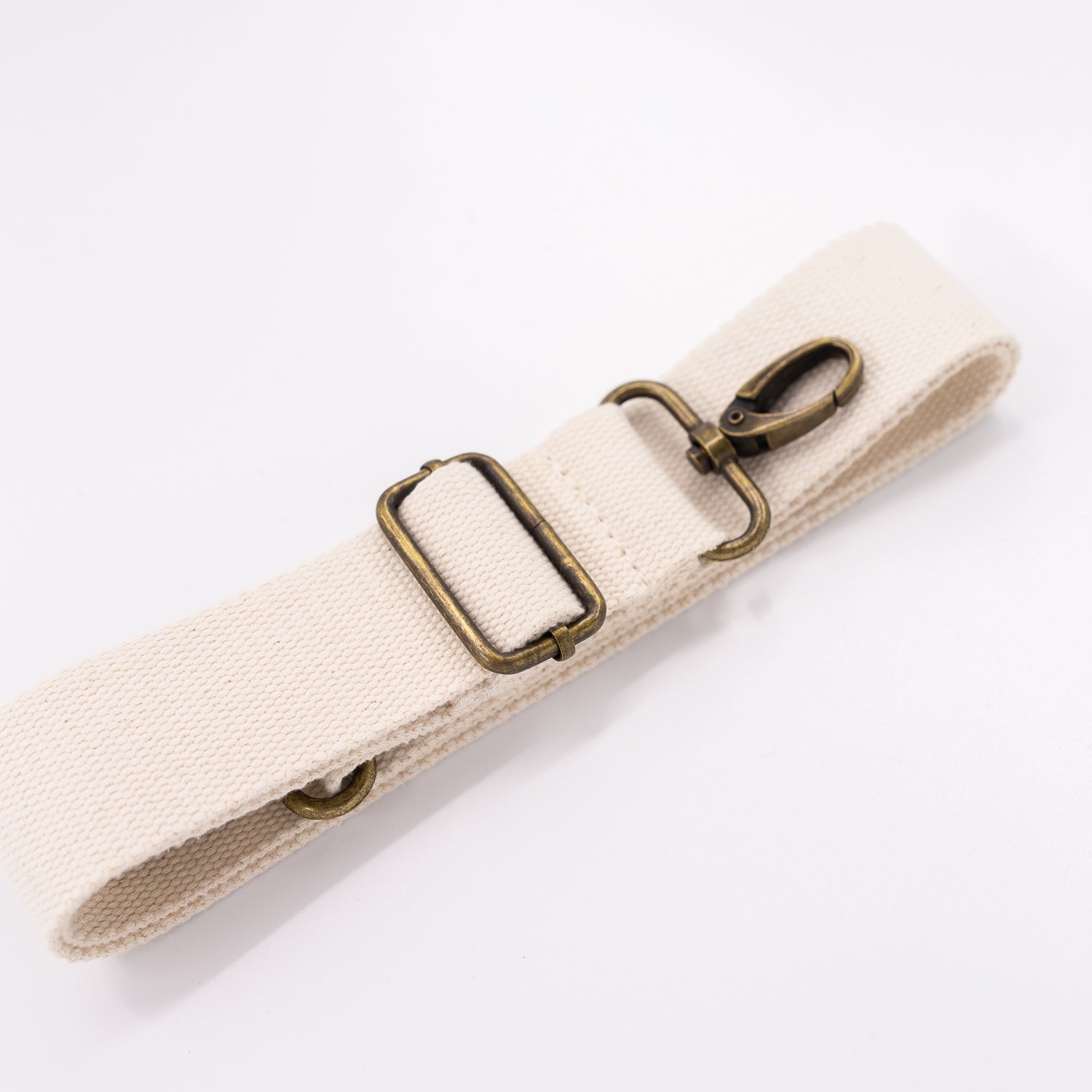 A cream cotton detachable strap with a metal clip for fanny packs.