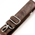 A close-up of a dark brown leather strap with silver-tone metal hardware, including a buckle, adjustment loops, and a swivel clasp, photographed on a clean white background.