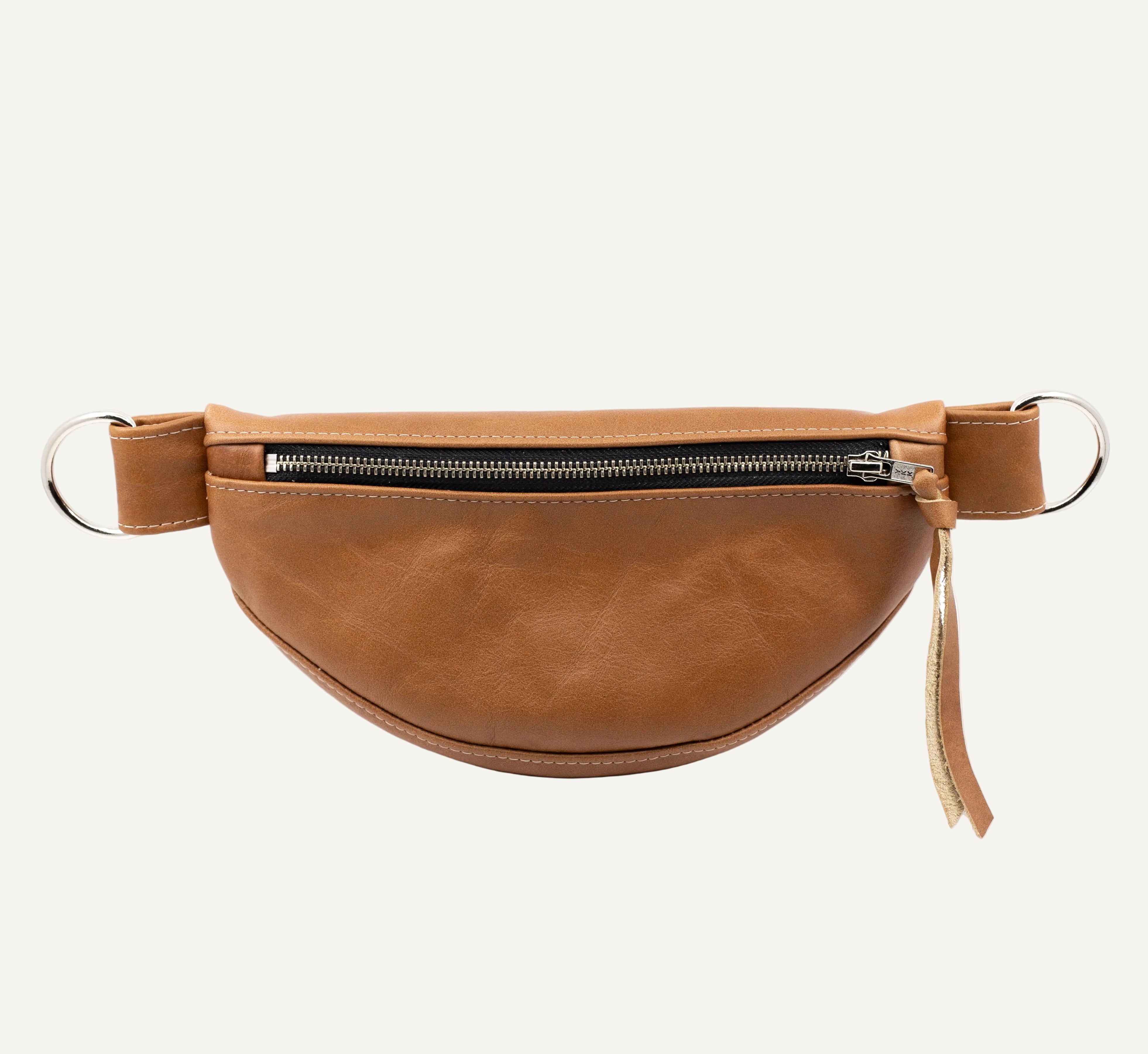 A tan faux-leather fanny pack with a curved body, a top zipper, and silver metal hardware, shown against a plain white background.