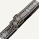 Black and white patterned belt with brass clip on a white background