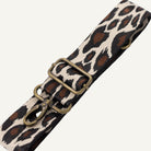 Leopard print strap with brass hardware on a white background