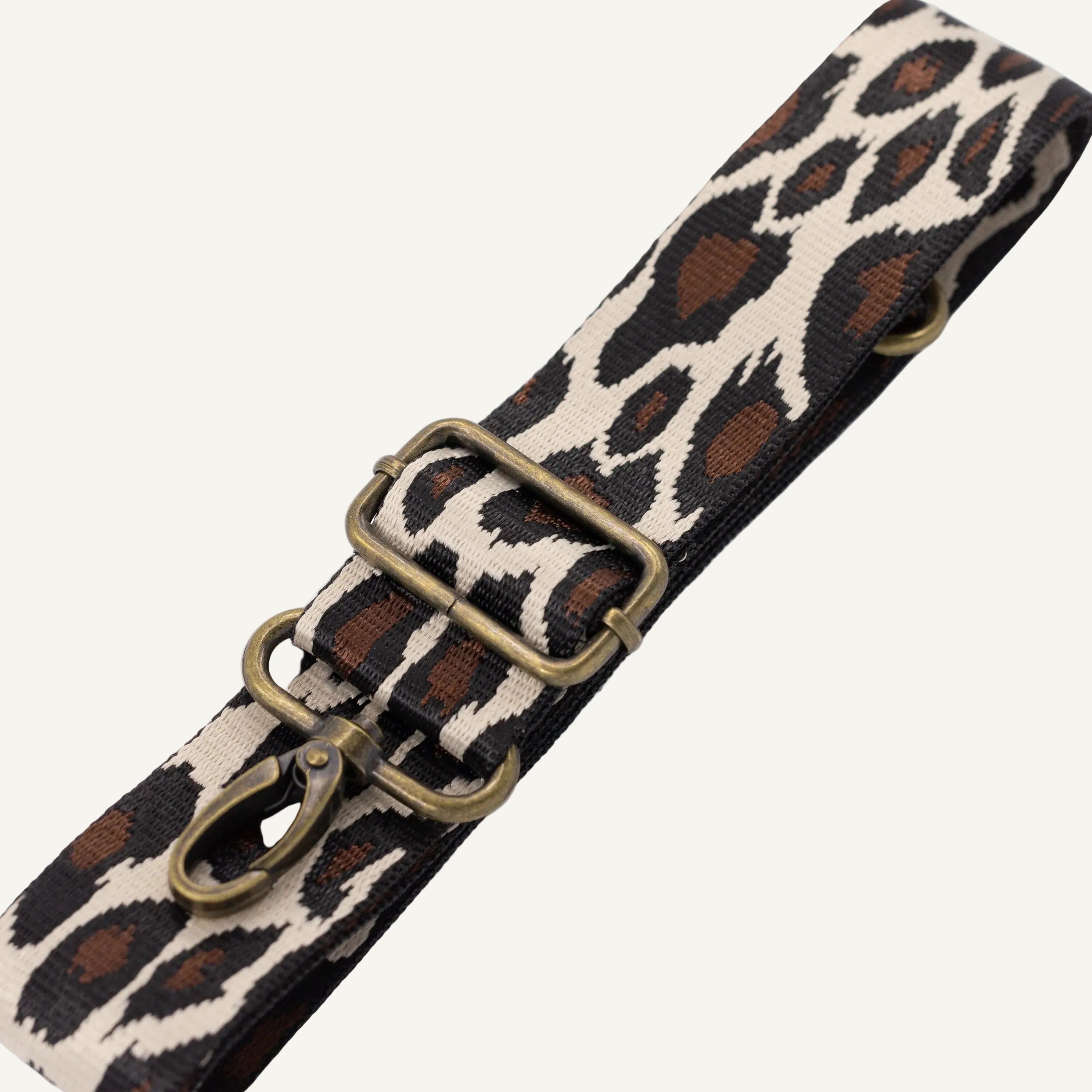 Leopard print strap with brass hardware on a white background