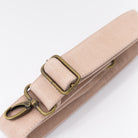 Light pink leather strap with brass clips on a white background