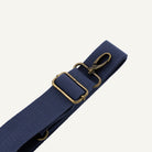 Navy blue strap with brass hardware on a white background