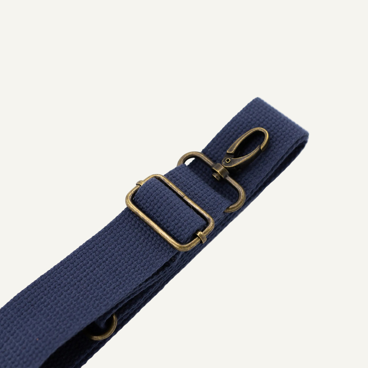Navy blue strap with brass hardware on a white background
