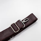 Brown leather strap with silver clips on a light gray background