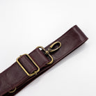 Maroon burgundy leather strap with brass clips on a white background