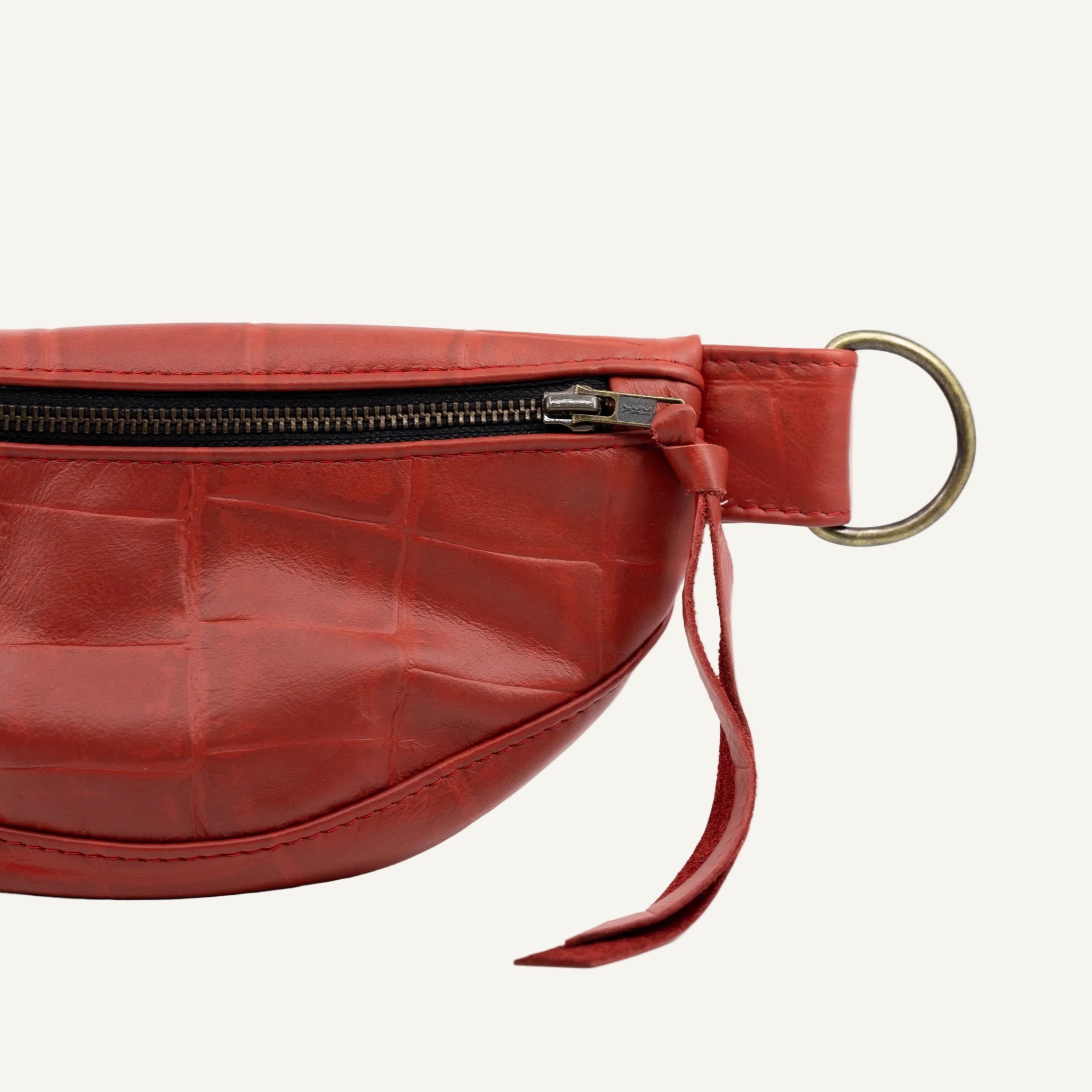 Red leather waist bag with a gold zipper on a white background