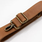 Brown leather strap with brass clips on a white background