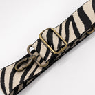 Zebra patterned strap with brass hardware on a white background