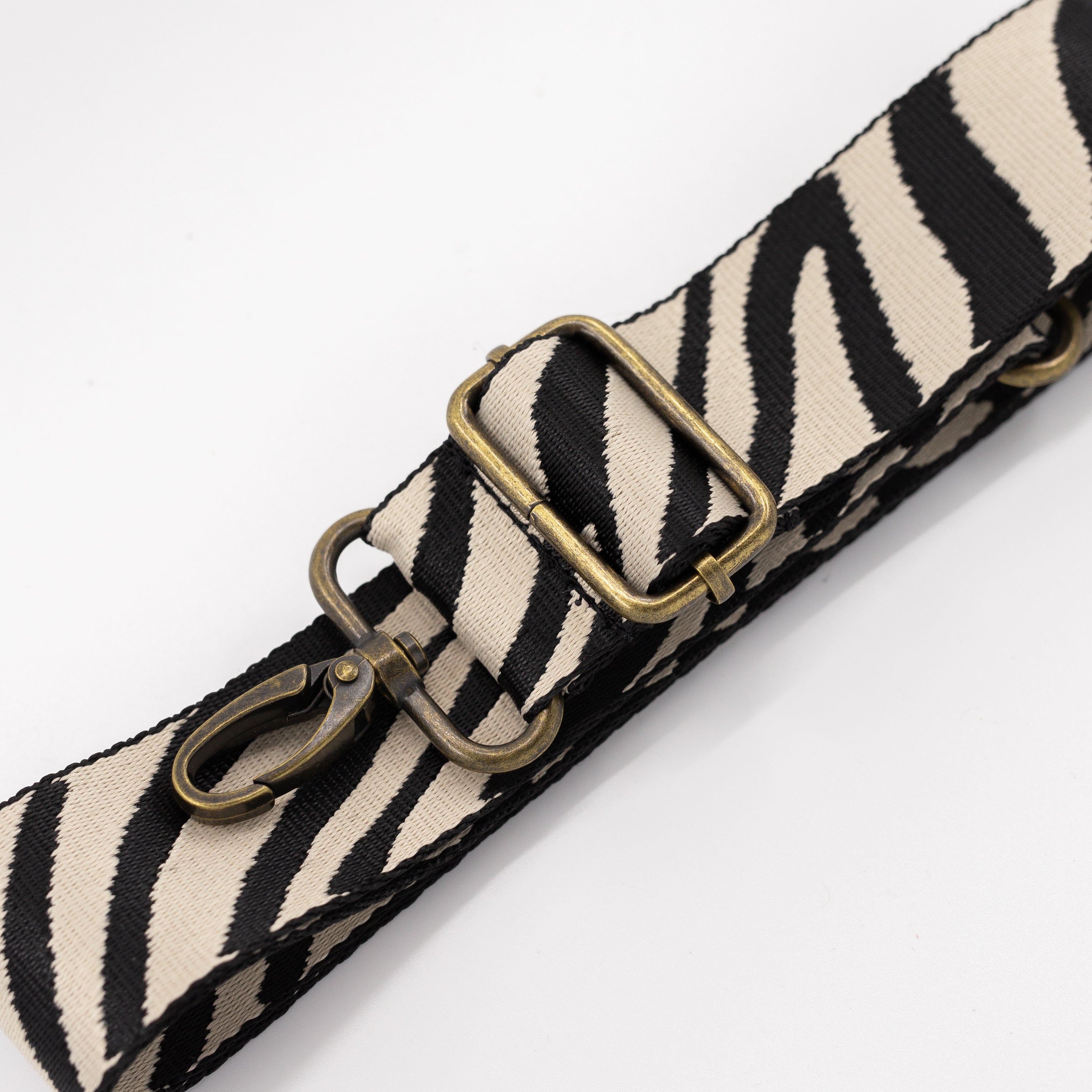 Zebra patterned strap with brass hardware on a white background
