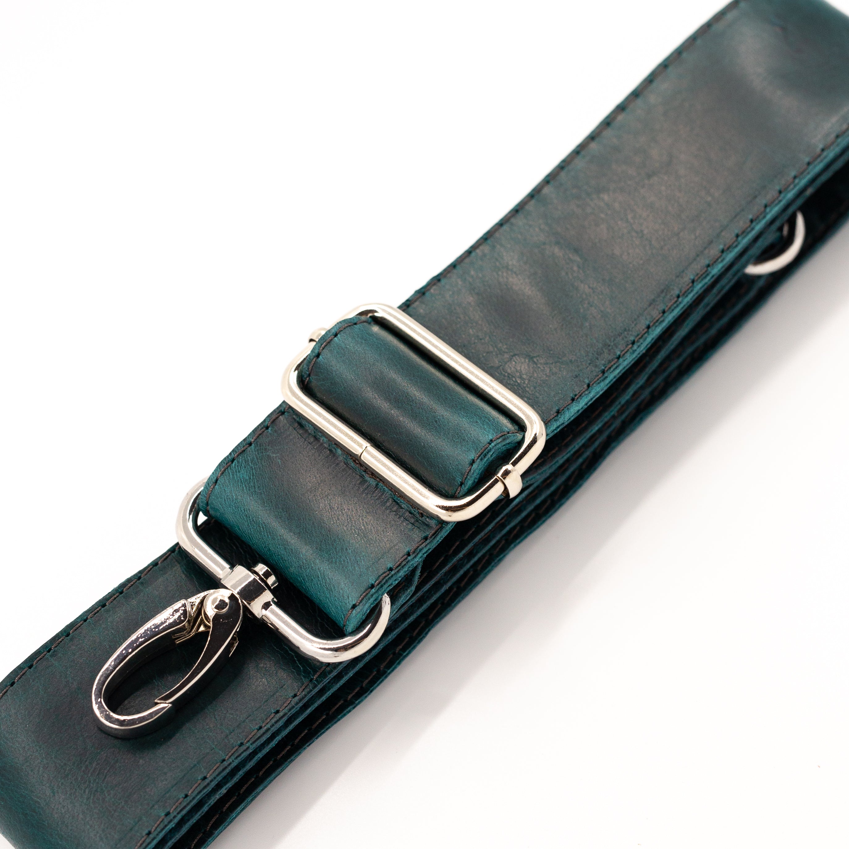 A close-up of a dark teal leather strap with silver-tone metal hardware, including a metal clasp, on a white background.