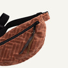 Brown textured waist bag with a black strap on a white background