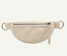 A cream-colored leather fanny pack with a silver zipper and gold-tone metal rings on a white background.