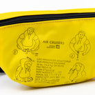 A close-up of a bright yellow life preserver instruction pouch featuring black printed diagrams and text explaining how to wear an air crocodile life preserver, with a black zipper along the top.