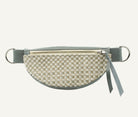 A half-moon fanny pack with a light blue gray leather strap and silver metal rings, shown against a plain white background.